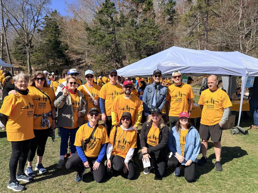 Members of the WCB team wearing yellow tshirts gathered together at the Steps for Life walk