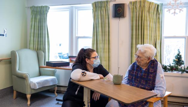 A health care worker talking to a resident in a care facility