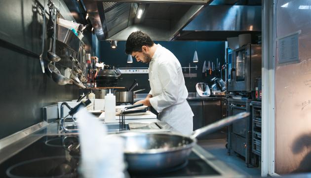 A chef cooking in the kitchen around sharp objects
