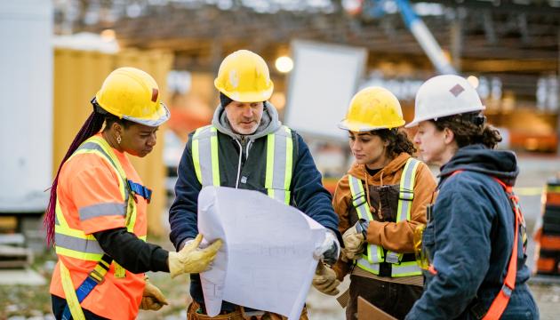 Construction workers with plan and hard hats