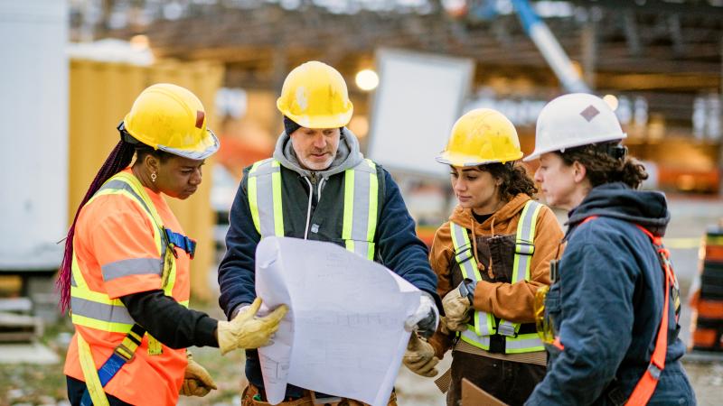 Construction workers with plan and hard hats