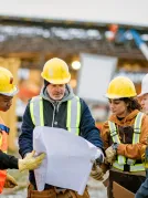 Construction workers with plan and hard hats