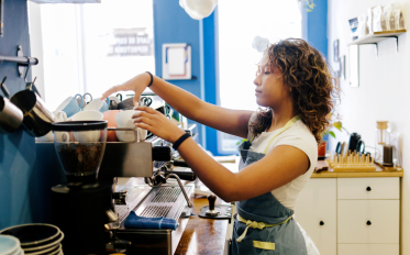 A young barista shown working on a coffee machine.