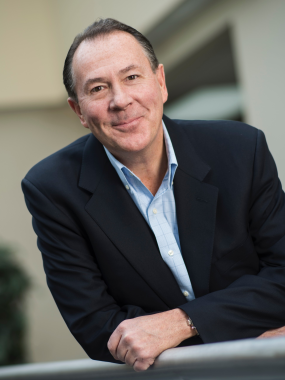 Standing shot of Tim McInnis, Worker Representative, standing and smiling in a black blazer.